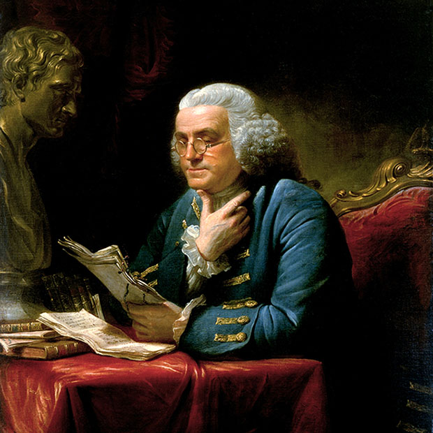 Benjamin Franklin reads at his desk wearing the wire-framed spectacles he helped develop, in a portrait painted in London in 1767.